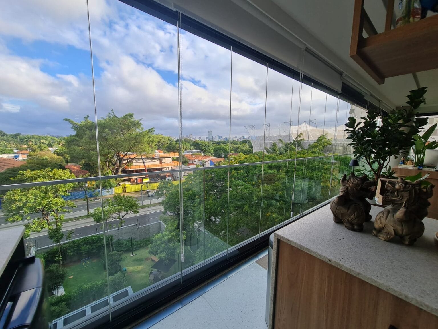 Sacada envidraçada com bancada e vista para a cidade